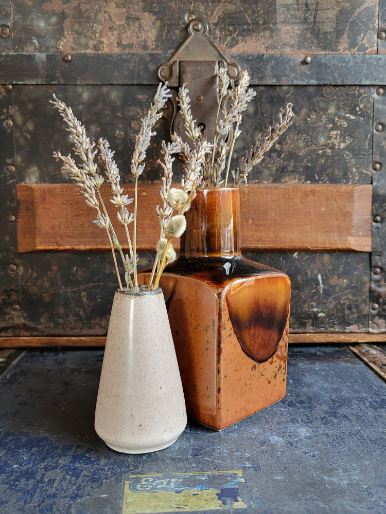 This image shows a couple of bud vases displayed with dried flowers.